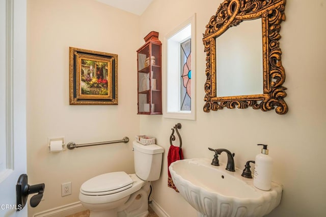 bathroom with baseboards, a sink, and toilet