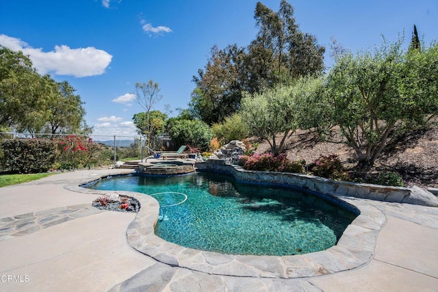 view of swimming pool with fence, a pool with connected hot tub, and a patio
