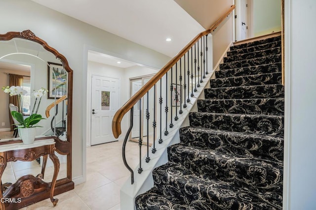 stairway featuring recessed lighting, arched walkways, tile patterned flooring, and baseboards