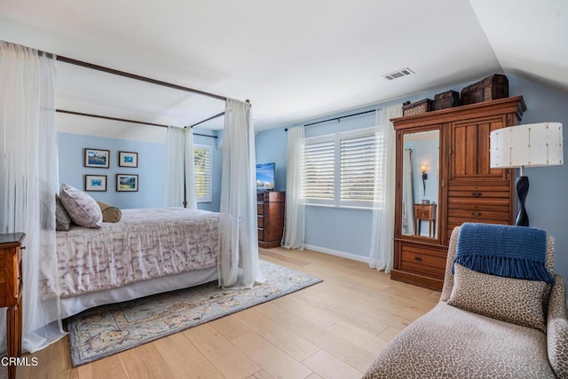 bedroom featuring lofted ceiling, wood finished floors, visible vents, and baseboards
