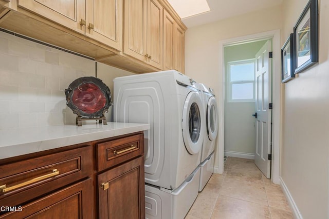 laundry room featuring baseboards, washer and dryer, light tile patterned floors, and cabinet space