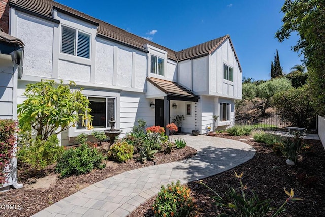 view of front of property featuring fence, a tiled roof, and stucco siding