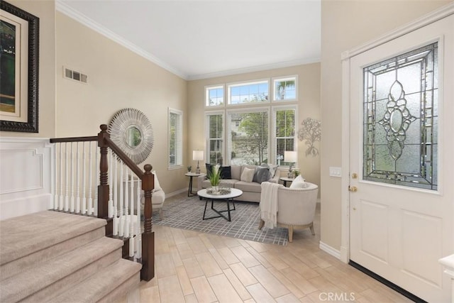 entryway featuring light wood-type flooring, baseboards, visible vents, stairs, and ornamental molding