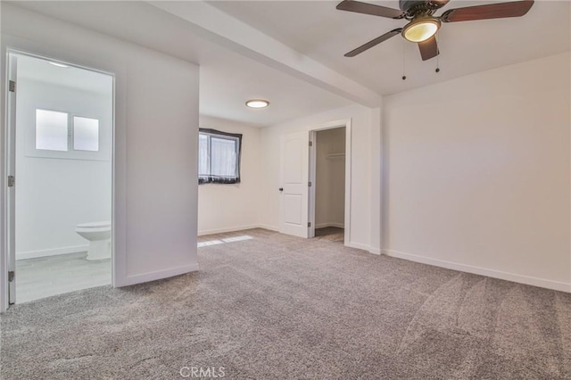 unfurnished bedroom featuring baseboards, ensuite bath, carpet flooring, and a ceiling fan