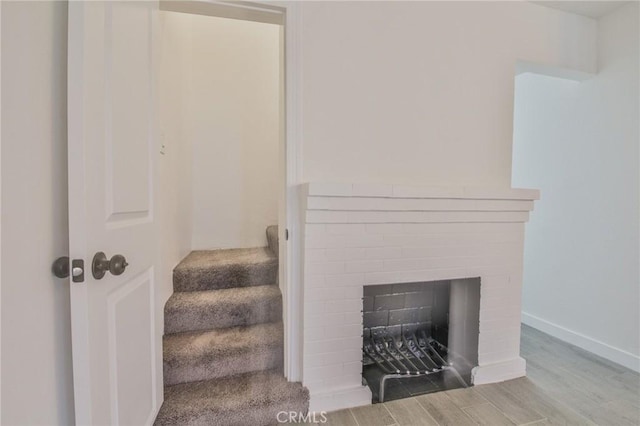 staircase with baseboards, a fireplace, and wood finished floors