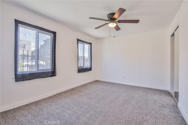 empty room featuring baseboards, carpet flooring, and a ceiling fan