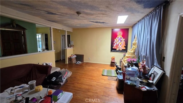 living room featuring baseboards, a textured ceiling, and wood finished floors