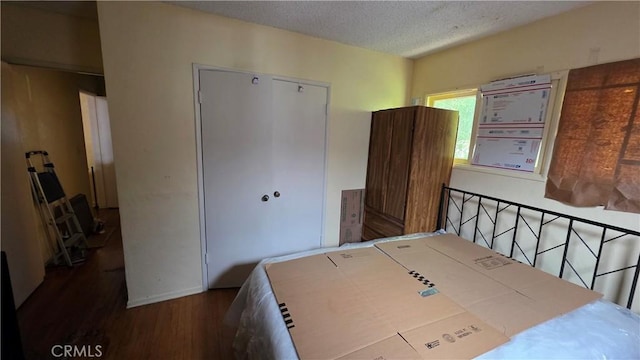 bedroom with a textured ceiling, a closet, and wood finished floors