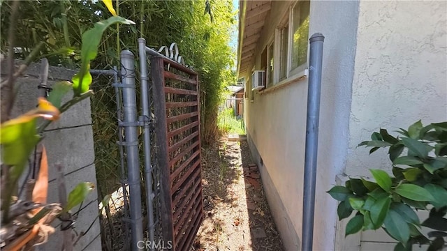 view of side of property featuring fence, a gate, and stucco siding