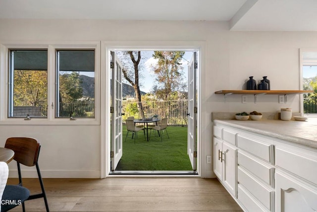 doorway with light wood finished floors and baseboards