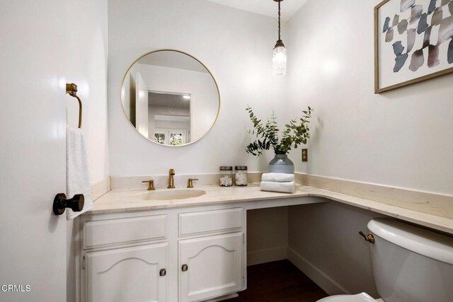half bath with vanity, toilet, and wood finished floors
