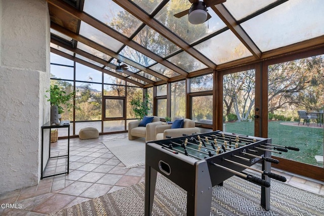 recreation room featuring high vaulted ceiling, expansive windows, stone tile floors, and a ceiling fan