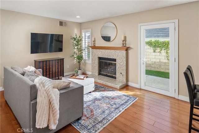 living room with baseboards, recessed lighting, wood finished floors, and a high end fireplace