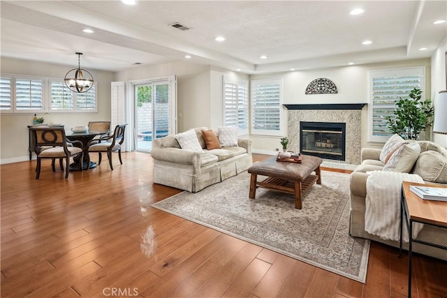 living area with baseboards, visible vents, wood finished floors, and an inviting chandelier