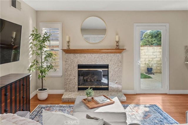 living area featuring baseboards, visible vents, wood finished floors, and a fireplace
