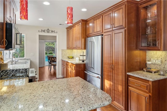 kitchen featuring appliances with stainless steel finishes, backsplash, light wood-style flooring, and a sink