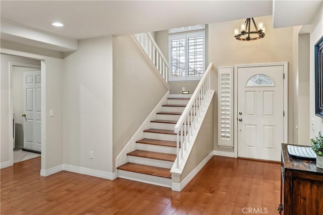 foyer with an inviting chandelier, wood finished floors, and baseboards