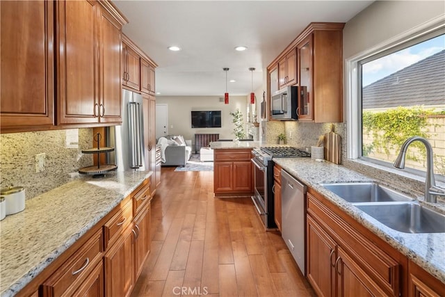 24118 Saint Moritz Dr, Valencia, CA 91355 - kitchen featuring stainless steel appliances, open floor plan, brown cabinets, wood-type flooring, and recessed lighting