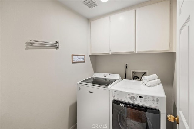 clothes washing area featuring separate washer and dryer, cabinet space, and visible vents