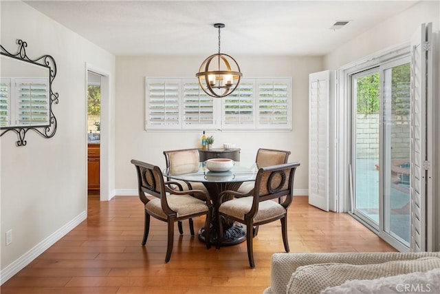 dining room with a chandelier, baseboards, visible vents, and light wood-style floors