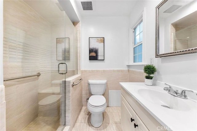 bathroom featuring a stall shower, vanity, tile walls, toilet, and visible vents