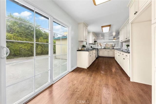 kitchen with dark wood-type flooring, dark countertops, a healthy amount of sunlight, and a sink