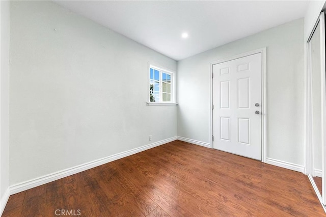 unfurnished bedroom with wood finished floors, baseboards, and a closet