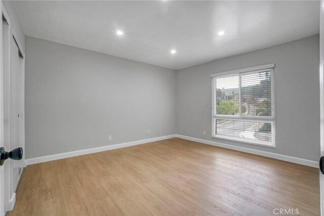 spare room with baseboards, recessed lighting, and light wood finished floors