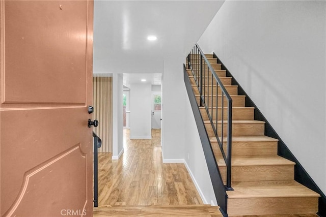 staircase with recessed lighting, baseboards, and wood finished floors