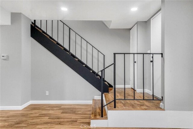 stairway featuring recessed lighting, baseboards, and wood finished floors