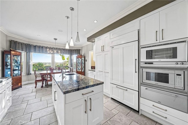kitchen with an island with sink, stone tile floors, built in appliances, and ornamental molding
