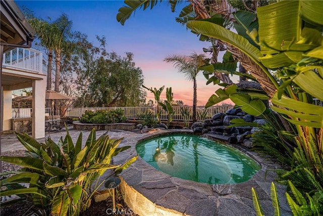 pool at dusk with a fenced in pool, a fenced backyard, and a patio