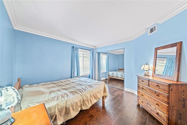 bedroom featuring crown molding, a closet, dark wood finished floors, baseboards, and visible vents