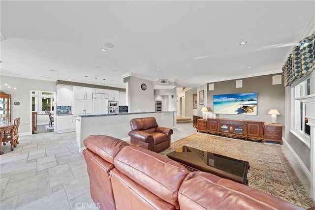 living room featuring baseboards, crown molding, a healthy amount of sunlight, and recessed lighting