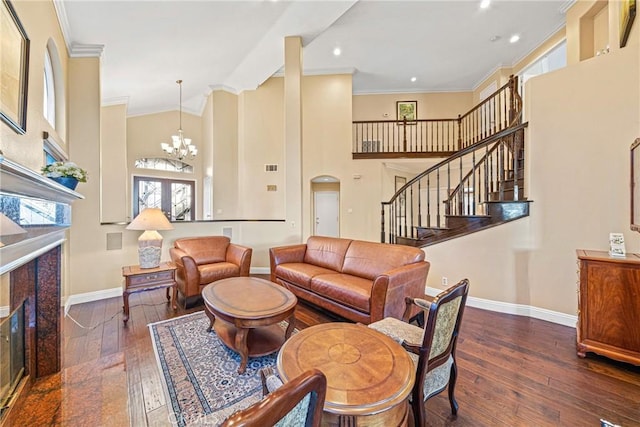 living room featuring ornamental molding, wood-type flooring, baseboards, stairs, and a notable chandelier