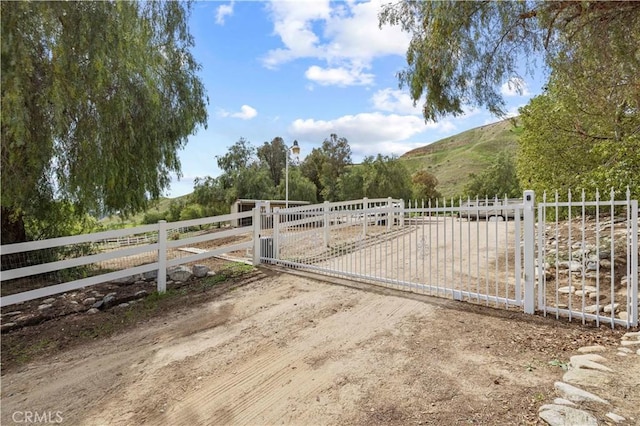 view of gate with a mountain view, fence, and a rural view