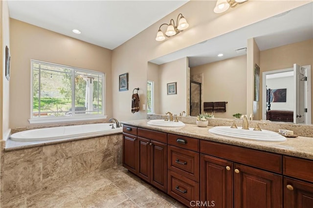 bathroom featuring double vanity, a garden tub, a sink, and a stall shower