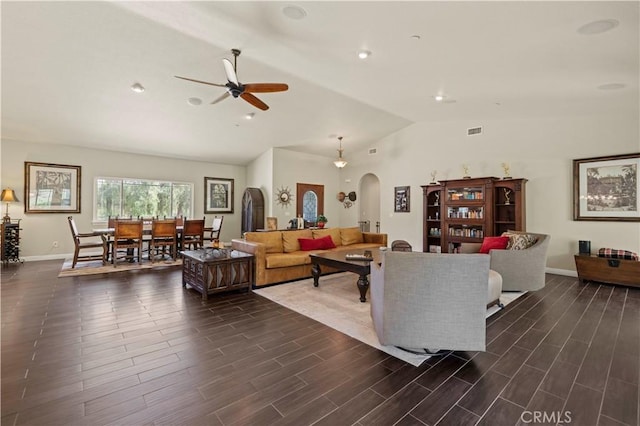 living room with visible vents, arched walkways, ceiling fan, dark wood finished floors, and lofted ceiling