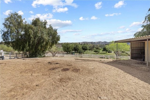 view of yard with an outbuilding, an enclosed area, an exterior structure, and a rural view