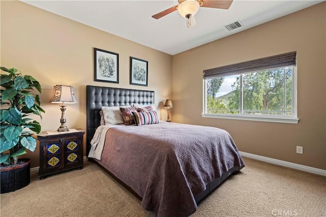 carpeted bedroom with visible vents, baseboards, and a ceiling fan