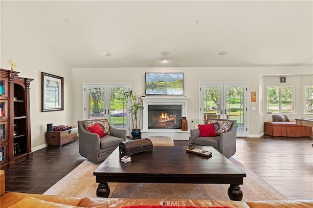 living room featuring dark wood-type flooring, french doors, baseboards, and a glass covered fireplace
