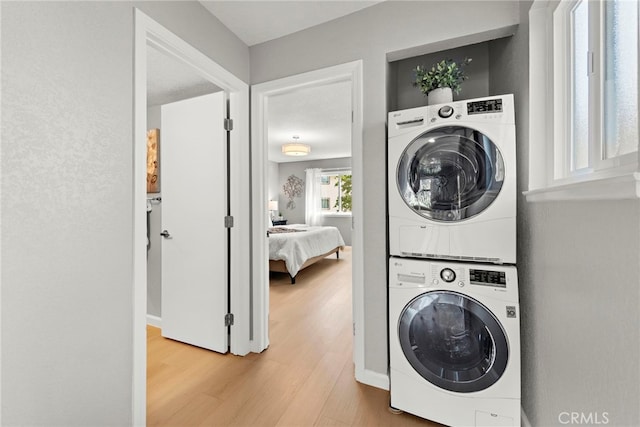 laundry room featuring stacked washer and clothes dryer, wood finished floors, and laundry area