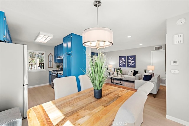 dining room featuring baseboards, visible vents, and light wood-type flooring