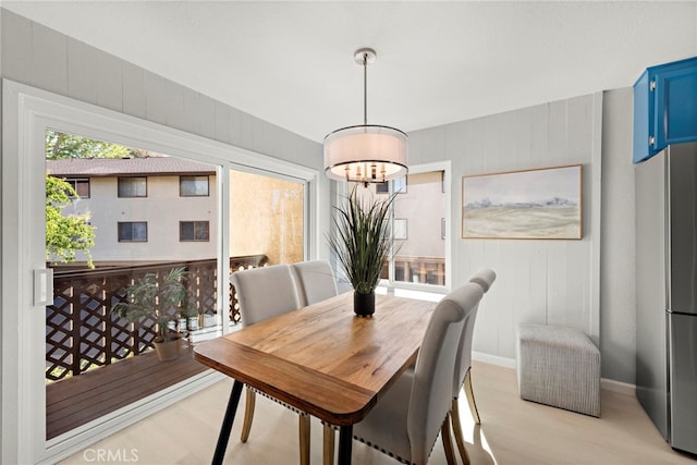 dining area with baseboards, light wood-style floors, and a chandelier