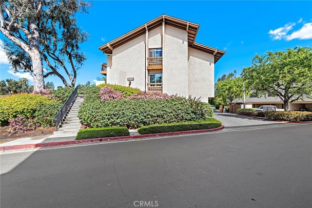view of side of property with stairs and stucco siding
