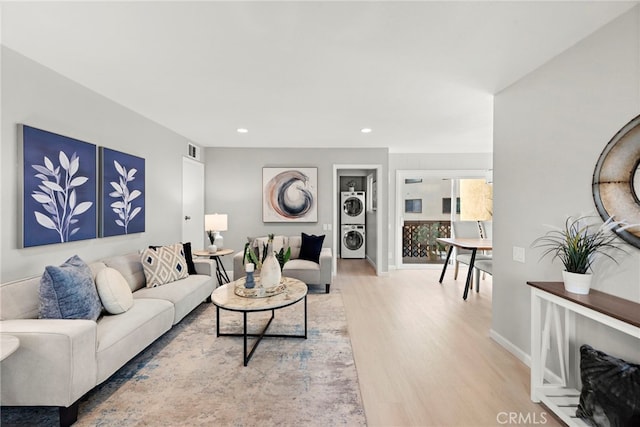 living area featuring visible vents, light wood finished floors, stacked washer and clothes dryer, baseboards, and recessed lighting