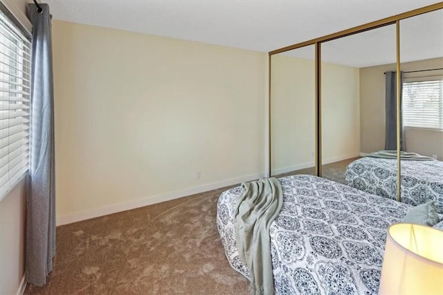carpeted bedroom featuring baseboards and a closet