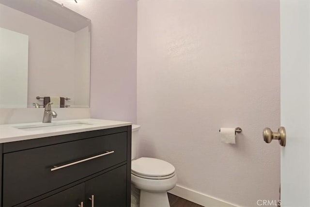 bathroom with toilet, baseboards, wood finished floors, and vanity