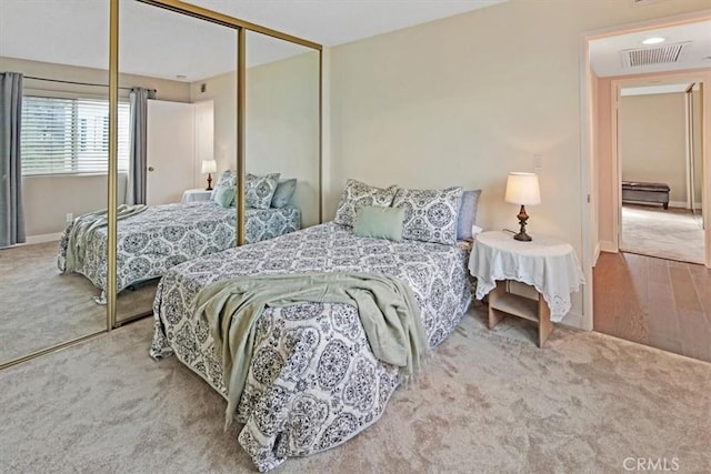 carpeted bedroom with baseboards, visible vents, and a closet