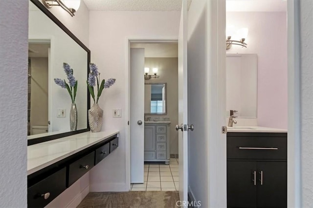 full bath featuring a textured ceiling, tile patterned floors, two vanities, and a sink
